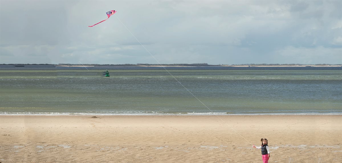 Meisje op strand met vlieger